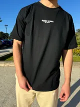 Remera negra de corte semi oversize con estampado frontal con la frase "Buena Vibra Est. 2022" en letras blancas.