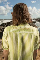 Camisa de lino a rayas verticales color naranja y blanco, de manga corta y corte oversize. Presenta bordados con motivos playeros en el frente y la espalda.