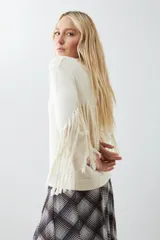 Sweater beige claro de tejido de punto con cuello redondo y mangas largas con flecos.