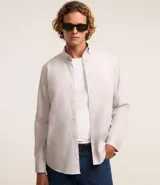Camisa de manga larga color beige claro, confeccionada en algodón. Tiene cuello camisero abotonado y botonadura frontal. Corte comfort de proporciones sueltas.