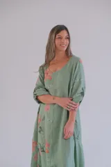 Vestido largo verde con estampado floral en tonos rosados y blancos, mangas 3/4 con ajuste de botón y ruedo irregular.