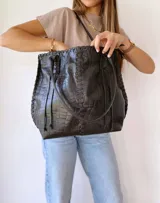 Bolso tote negro de cuero con textura tipo cocodrilo, doble asa larga y forro de tela.