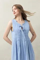 Vestido corto de lino color celeste claro, con escote con lazo ajustable y detalle de alforzas verticales en el frente.