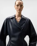 Chaqueta estilo biker de efecto cuero color azul marino, con solapa ancha, cierre cruzado frontal y cintura entallada. Presenta mangas largas y bolsillos delanteros con cremallera invisible.