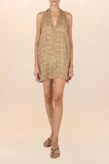 Vestido corto con estampado abstracto en tonos amarillos, marrones y violetas, con cuello halter que se ata al cuello y espalda descubierta.