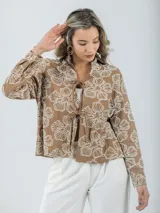Blusa color crudo con bordados florales, cuello camisero y mangas largas.