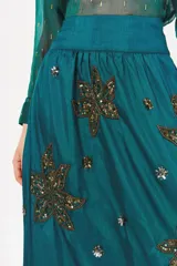 Falda larga color verde azulado con cintura alta y bordados dorados y plateados con forma de hojas.