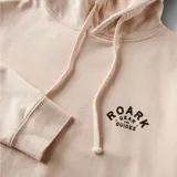 Canguro color crema con capucha, cordones ajustables, bolsillo tipo canguro y logo estampado en el pecho.