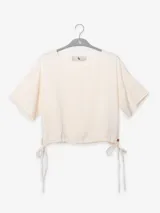 Remera color crema de mangas cortas con cuello redondo y cordones ajustables en la cintura.