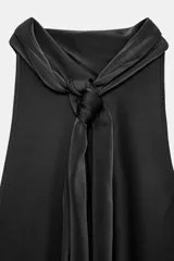 Top sin mangas color blanco, con cuello halter drapeado y bajo asimétrico con caída.