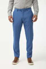 Ambo de traje azul marino, compuesto por saco de solapa en punta y pantalón a juego. Se combina con una camisa azul oscuro desabrochada.