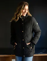 Campera negra acolchada con capucha con borde de piel sintética negra desmontable, cierre frontal con cremallera y botones a presión dorados, bolsillos laterales y puños elásticos.