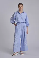 Camisa celeste con bordados de flores blancas en mangas y ruedo.