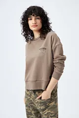 Buzo color marrón de corte relajado confeccionado en tejido de algodón con interior suave al tacto. Presenta detalle de estrella con tachas en la espalda y bordado delantero con la frase Dreamer – Born to rock.