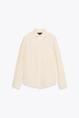 Camisa color crema de algodón y lyocell, con cuello solapa, manga larga con puños y bolsillo de parche en el pecho.