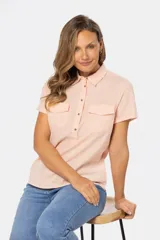 Camisa de lino color salmón, de corte clásico, con cuello camisero, medio abotonado, manga corta y dos bolsillos de parche en el pecho.