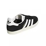 Championes Adidas Gazelle negros con las tres tiras blancas y detalles dorados.