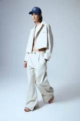 Campera corta color beige confeccionada en gabardina con lazo para ajustar en cintura, botones de pasta en charreteras y chapa RENÉE cursiva cosida a mano en el delantero.