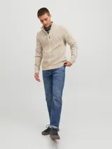 Sweater de punto color beige con cuello alto, cierre parcial con tres botones de madera y diseño con patrón de rombos y trenzas.