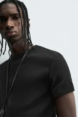 Camiseta negra de corte slim fit, cuello redondo y manga corta. Confeccionada en tejido de algodón con elasticidad y acabados en rib.