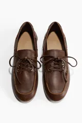 Zapatos náuticos de cuero marrón con cordones y costura de mocasín adelante. Forro en lona de algodón.