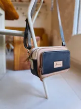 Bandolera rectangular combinada en color negro, beige y blanco, con correa larga regulable y bolsillo exterior con cierre.