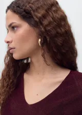 Jersey de punto fino color vino tinto, con cuello pico y manga larga. Tejido de lúrex con acabado brillante.