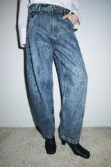 Jeans de tiro alto, estilo balloon leg, largo completo. Denim azul claro con efecto lavado ácido o 'acid wash'. Presenta cinco bolsillos y cierre frontal con cremallera y botón.