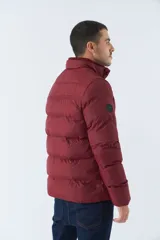 Campera inflada azul marino de nylon con cuello alto, cierre frontal con cremallera, bolsillos laterales con cierre y logo estampado en el pecho. El modelo usa talle M.