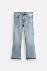 Pantalón de jean celeste, corte flare, con cinco bolsillos, efecto lavado, bajo irregular y cierre frontal con cremallera y botón.