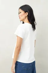 Remera blanca de algodón con cuello redondo y costuras verticales en el frente.