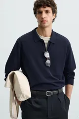 Polo de manga larga color negro, tejido en hilatura con mezcla de algodón y seda, de corte regular fit, con cuello solapa y cierre frontal de botonadura.