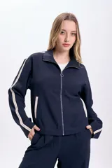 Campera azul marino con cierre frontal, capucha y dos líneas blancas verticales en las mangas.