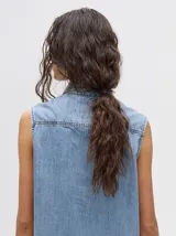 Camisa sin mangas de denim liviano color camel, con cuello camisero y botones frontales. Presenta bordados temáticos marinos en el pecho, incluyendo un sol, olas, una gaviota y vida marina.