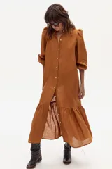 Vestido largo color marrón de lino, con cuello mao, mangas 3/4 abullonadas con puños elásticos y falda con volantes.