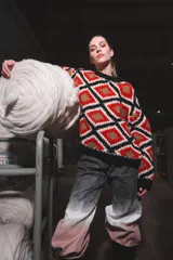 Sweater tejido de lana con diseño geométrico de rombos en colores rojo, blanco, negro y dorado.