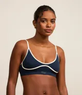 Soutien deportivo azul con breteles finos ajustables, base larga y detalles contrastantes en color blanco.