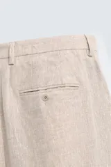 Pantalón de vestir color beige claro, confeccionado en lino, de corte recto, con bolsillos laterales y traseros.
