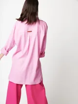 Camisa oversized color rosado, con largo por debajo de la cadera, mangas largas y bolsillo con detalle bordado.