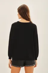 Sweater negro de moldería holgada, liviano y de caída relajada. Con aplicación de tachas termofijadas que expanden desde el hombro hacia el bajo ruedo de forma radial.
