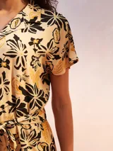 Mono corto negro con cuello camisero, cierre frontal con botones y lazo en la cintura.