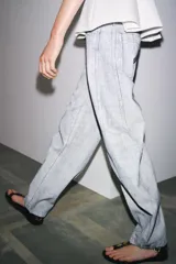 Pantalón de jean de tiro medio con pierna ancha y corte tapered, confeccionado en tejido de algodón revestido color gris claro. Cuenta con bolsillos delanteros y traseros, trabillas en la cintura y cierre frontal con cremallera y botón.