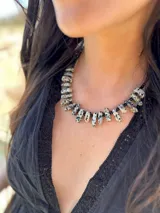 Collar corto con cuentas de piedra natural blanca con manchas negras y mostacillas negras. Se cierra con cadena de acero quirúrgico y gancho para regular el largo.