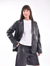 Chaqueta tipo blazer de cuero sintético color negro, con solapas de muesca, cierre frontal con un botón, bolsillos laterales y corte holgado.