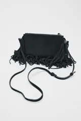 Bandolera marrón de serraje con flecos largos en la parte inferior. Tiene asa de hombro y bandolera extraíbles, doble bolsillo interior y cierre con cremallera.