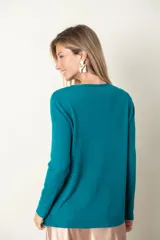 Buzo fino color verde, con detalle de bolsillo y botón de strass en el frente.