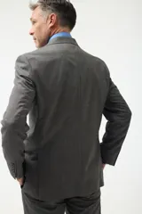 Ambo de vestir gris con saco de dos botones, solapa de muesca, dos bolsillos con solapa y un bolsillo de ojal en el pecho. Pantalón de vestir a juego, de corte recto.