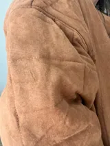 Campera color camel de corte relajado, con exterior de tejido efecto gamuza e interior acolchado. Tiene cuello alto, cierre frontal con cremallera, bolsillos laterales y bolsillo interno.