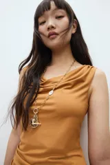 Vestido midi color ocre, sin mangas, de punto elástico con leve brillo. Modelo ajustado con frunces en escote, hombros y en un lateral de la cintura para crear un efecto drapeado.