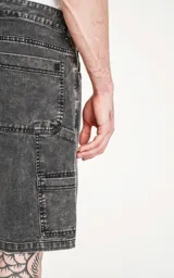 Bermuda de denim gris con efecto lavado, calce oversize estilo carpintero y bolsillo lateral.